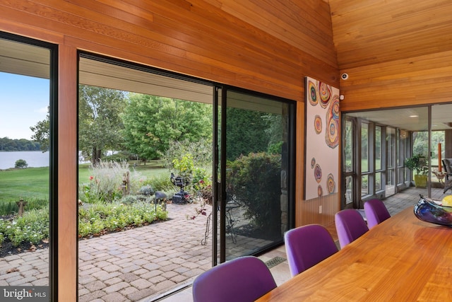 doorway with plenty of natural light, a water view, light tile patterned floors, and wooden walls