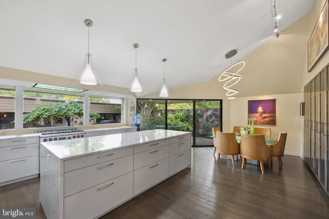 kitchen with pendant lighting, lofted ceiling, a kitchen island, dark hardwood / wood-style flooring, and white cabinetry