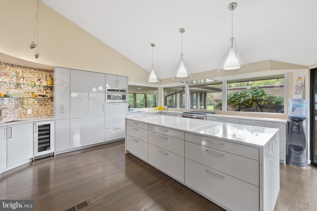 kitchen featuring decorative light fixtures, a kitchen island, white cabinetry, and beverage cooler