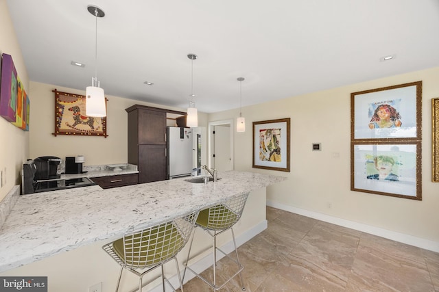 kitchen featuring a breakfast bar, sink, white fridge, and pendant lighting