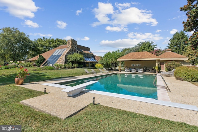 view of pool featuring a diving board, a yard, and a patio