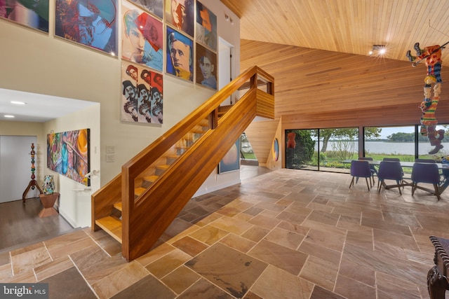 stairs featuring wood walls, high vaulted ceiling, and wood ceiling