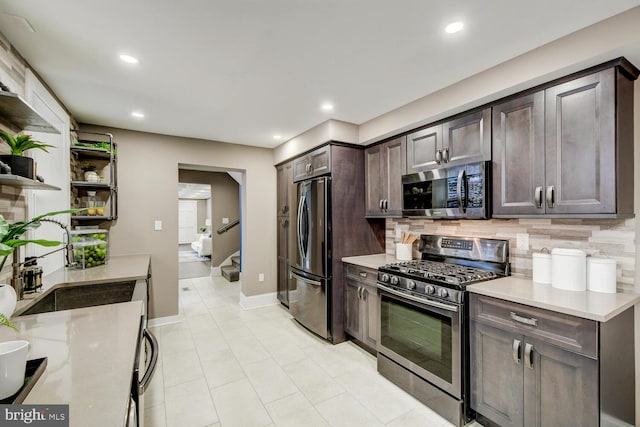 kitchen with appliances with stainless steel finishes, tasteful backsplash, light tile patterned floors, dark brown cabinetry, and sink