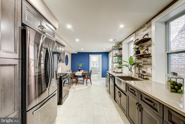 kitchen with dark brown cabinets, light tile patterned flooring, sink, stainless steel appliances, and backsplash