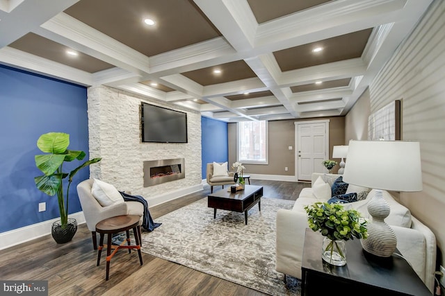 living room featuring beamed ceiling, dark hardwood / wood-style floors, coffered ceiling, a stone fireplace, and ornamental molding