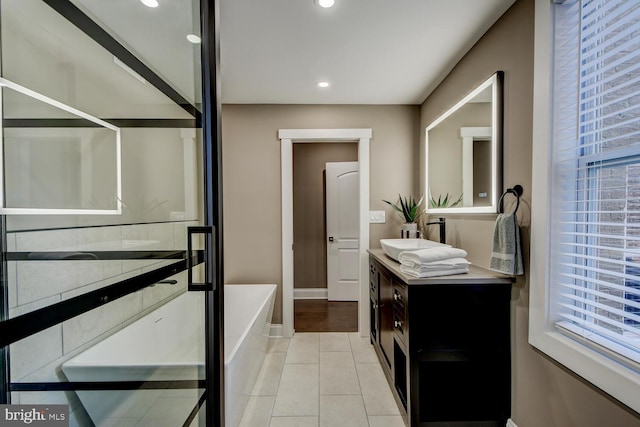 bathroom with tile patterned flooring, a bath, and vanity