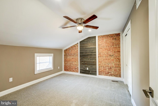 additional living space with vaulted ceiling, ceiling fan, brick wall, and carpet flooring