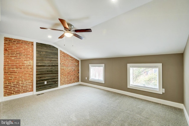 empty room with brick wall, lofted ceiling, carpet, and ceiling fan