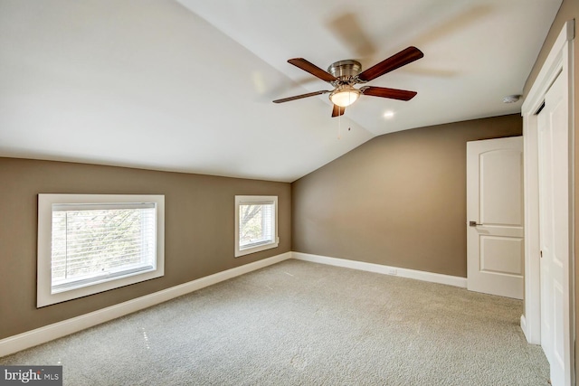 additional living space featuring a wealth of natural light, vaulted ceiling, ceiling fan, and light colored carpet