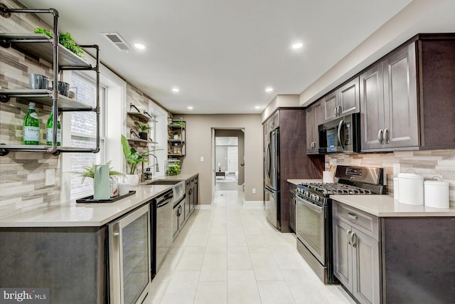 kitchen with backsplash, stainless steel appliances, dark brown cabinets, beverage cooler, and sink