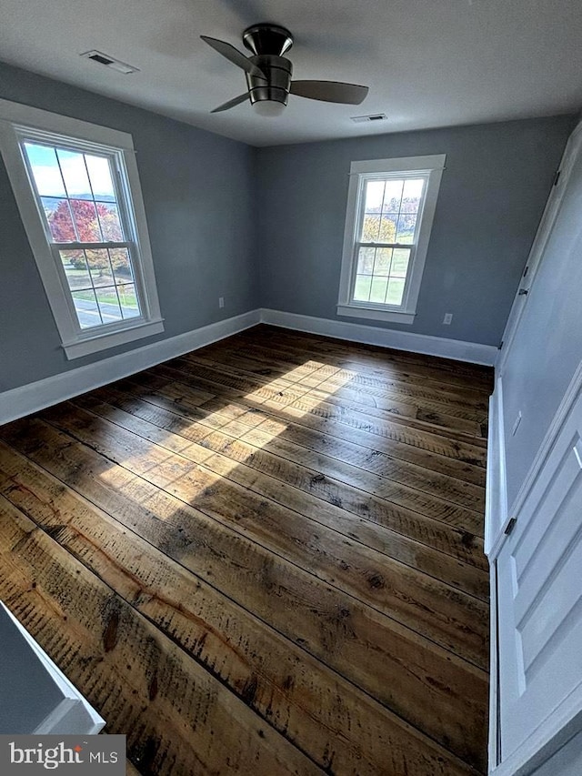 unfurnished bedroom featuring a ceiling fan, visible vents, baseboards, and dark wood finished floors