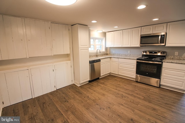 kitchen with white cabinetry, a sink, appliances with stainless steel finishes, and dark wood-type flooring