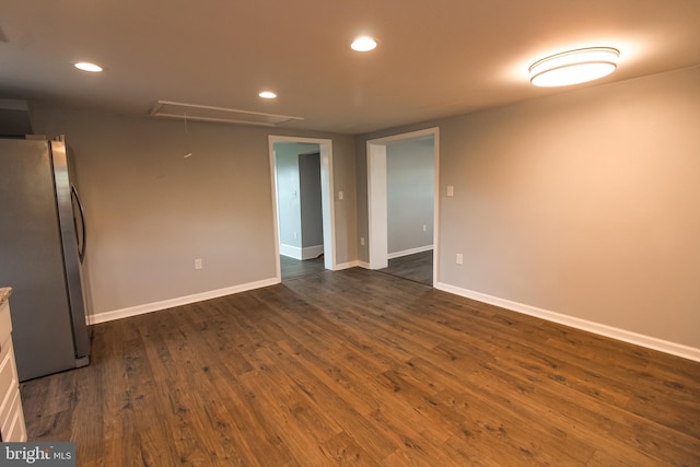 spare room with recessed lighting, dark wood-type flooring, attic access, and baseboards