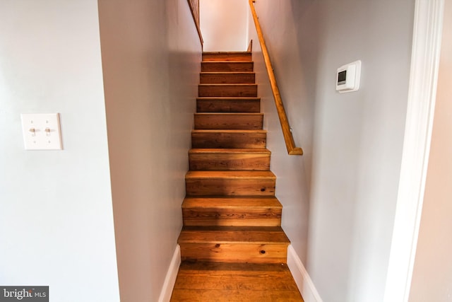 staircase featuring baseboards and wood finished floors
