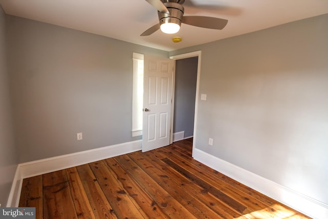 spare room with baseboards, dark wood-type flooring, and a ceiling fan