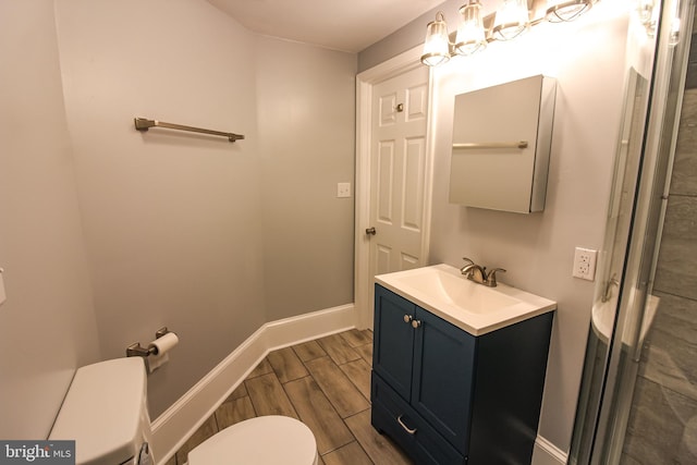 bathroom featuring baseboards, toilet, wood finish floors, and vanity