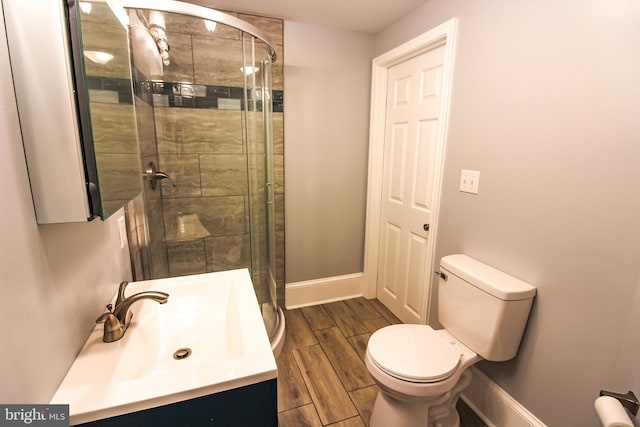 bathroom featuring a shower stall, baseboards, toilet, vanity, and wood tiled floor