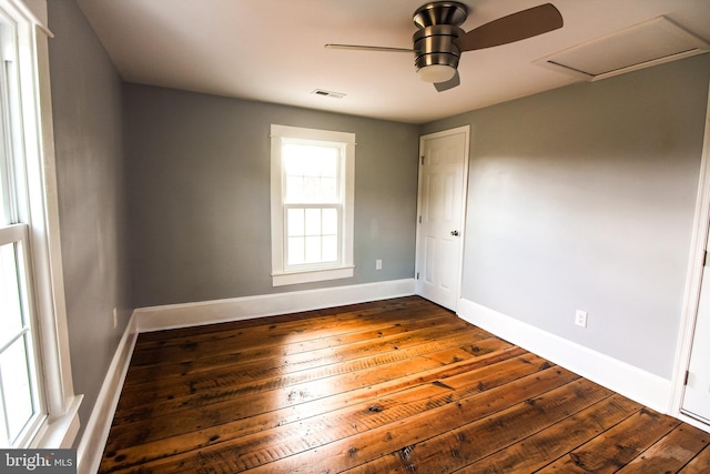 unfurnished room with visible vents, baseboards, a ceiling fan, attic access, and dark wood-type flooring