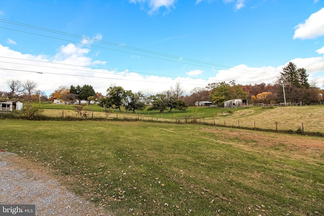 view of yard with fence and a rural view