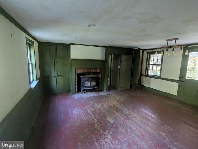 unfurnished living room featuring ornamental molding, a wood stove, and dark wood-type flooring