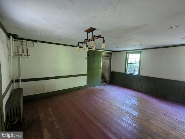 empty room featuring radiator heating unit and hardwood / wood-style flooring