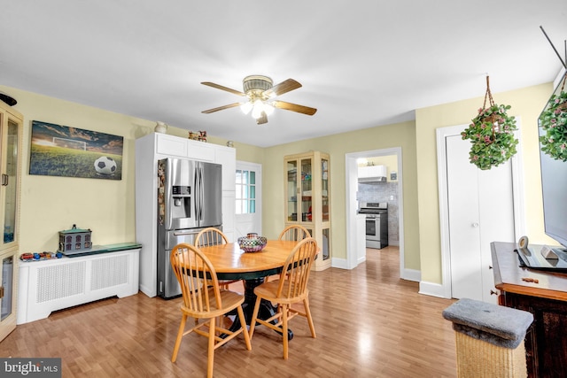 dining room featuring light hardwood / wood-style floors, ceiling fan, and radiator