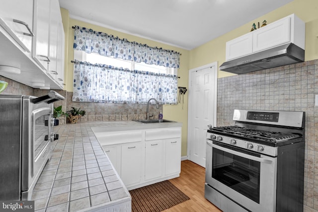 kitchen featuring light hardwood / wood-style floors, white cabinetry, range hood, and gas stove