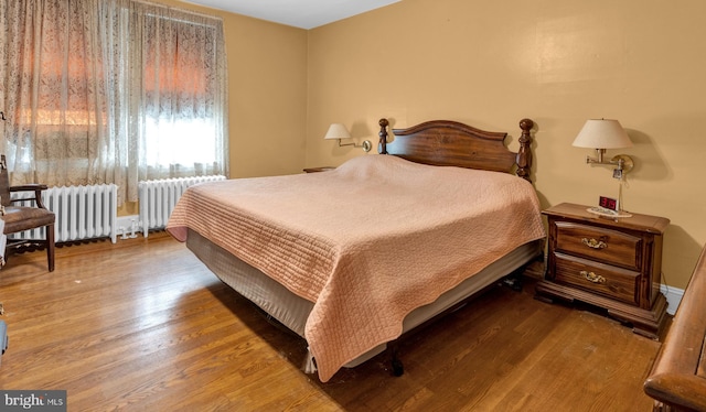 bedroom with hardwood / wood-style floors and radiator heating unit