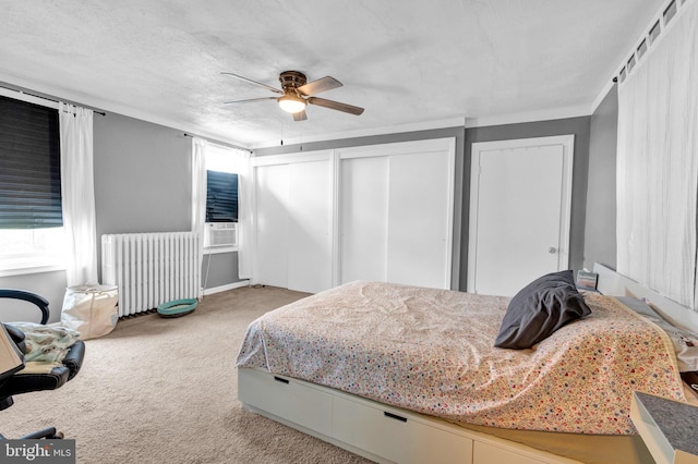 carpeted bedroom with a textured ceiling, radiator heating unit, and ceiling fan