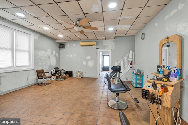 exercise area featuring a wealth of natural light, ceiling fan, a paneled ceiling, and an AC wall unit