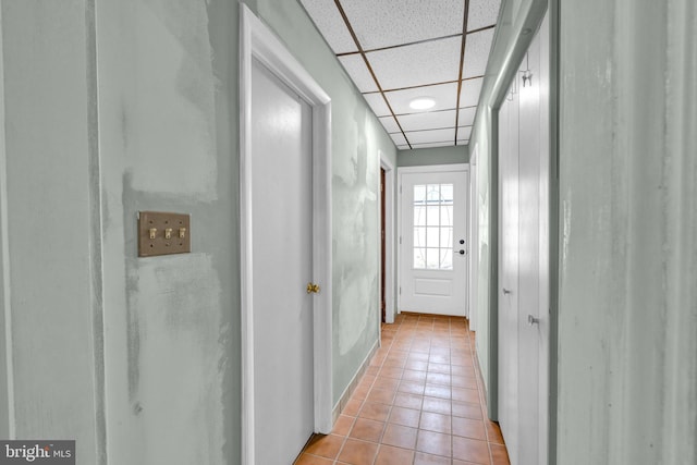 hall with a drop ceiling and light tile patterned flooring