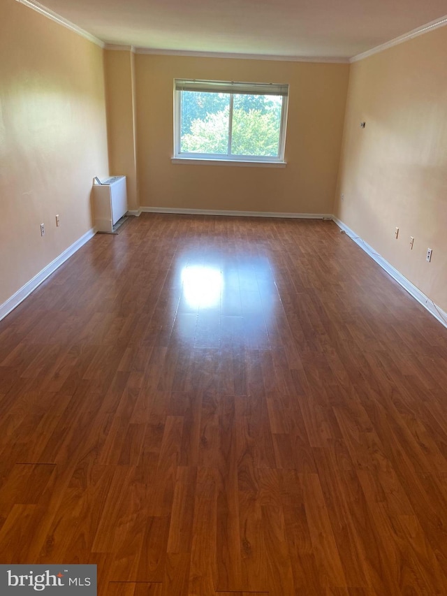 unfurnished room featuring dark wood-type flooring and crown molding