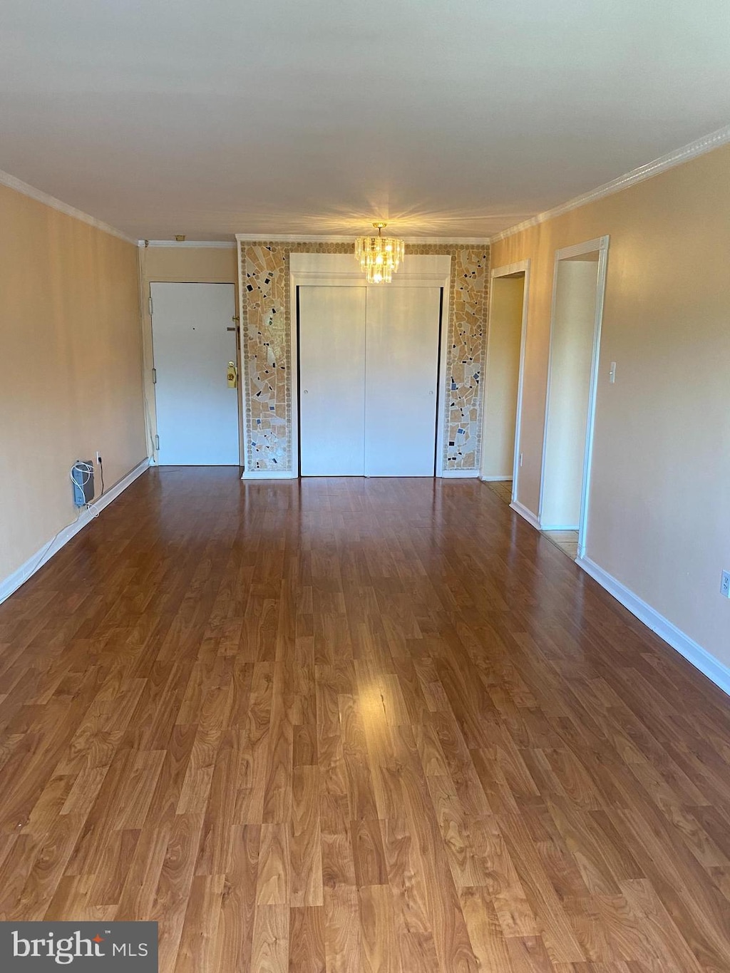 unfurnished bedroom with a chandelier, hardwood / wood-style floors, and crown molding