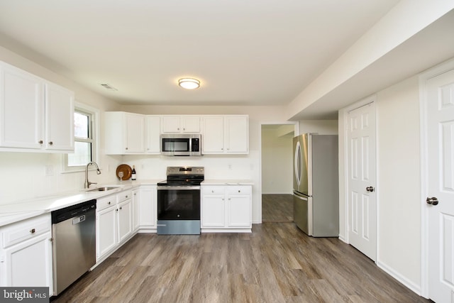 kitchen with white cabinets, sink, light wood-type flooring, and stainless steel appliances