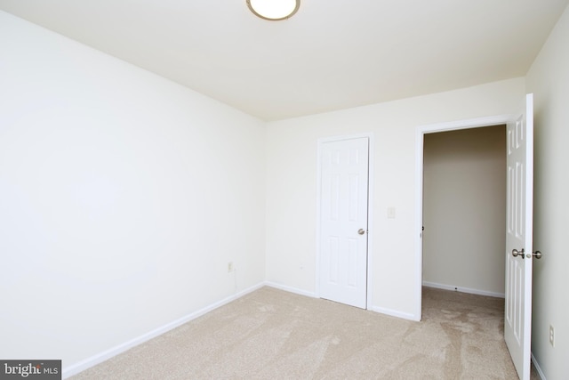 unfurnished bedroom featuring light colored carpet and a closet