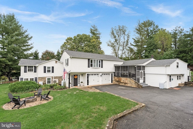 view of front of house featuring a front yard, a sunroom, and an outdoor fire pit