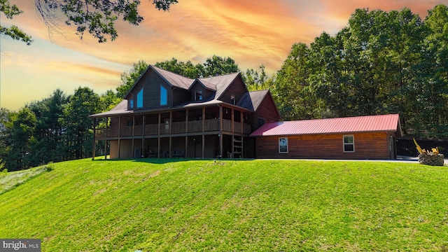 back house at dusk featuring a lawn