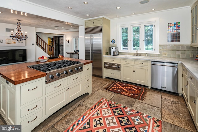 kitchen featuring decorative backsplash, sink, pendant lighting, a notable chandelier, and appliances with stainless steel finishes