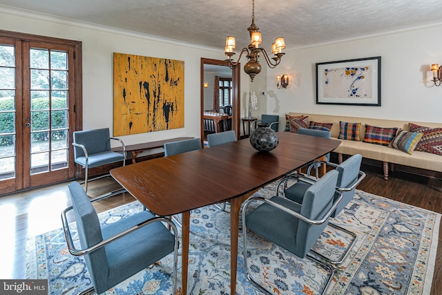 dining space featuring a notable chandelier, crown molding, hardwood / wood-style floors, and a textured ceiling