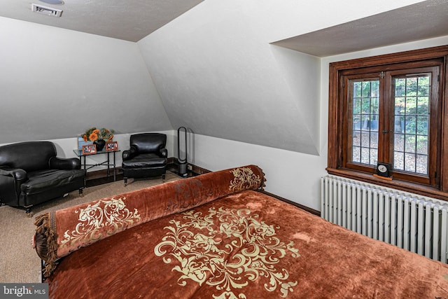 bedroom with a textured ceiling, radiator, vaulted ceiling, and carpet flooring