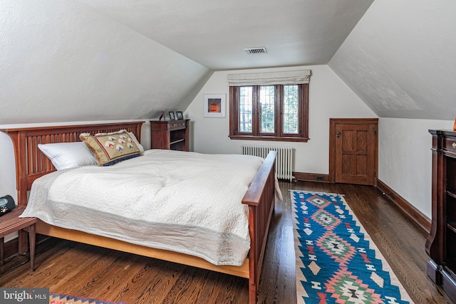 bedroom with dark wood-type flooring, lofted ceiling, and radiator