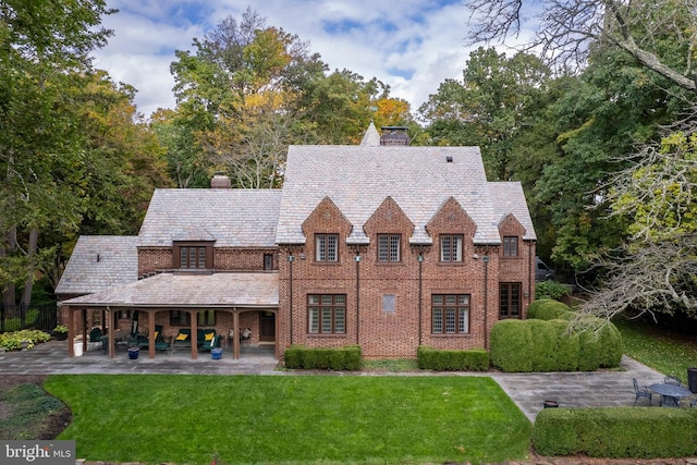 tudor home with a front lawn and a patio