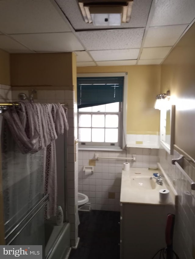 full bathroom with tile walls, a paneled ceiling, vanity, and toilet