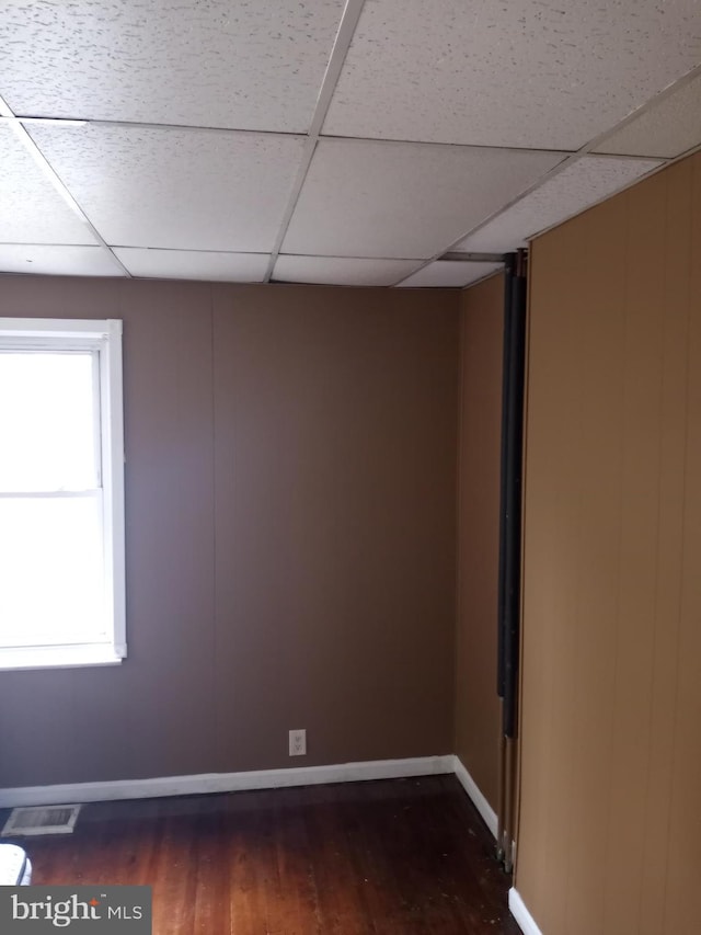 unfurnished room with a drop ceiling and dark wood-type flooring