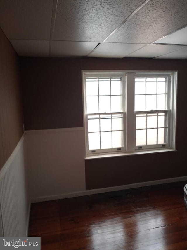 spare room featuring dark wood-type flooring and a paneled ceiling