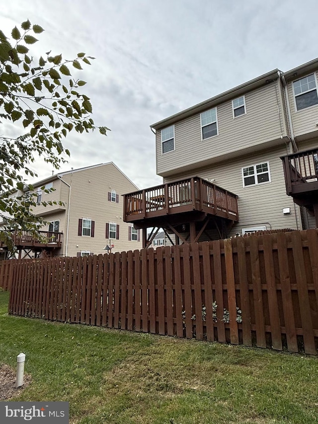 rear view of house featuring a deck and a yard