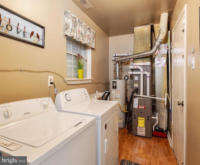 clothes washing area featuring gas water heater, light wood-type flooring, and washer and dryer