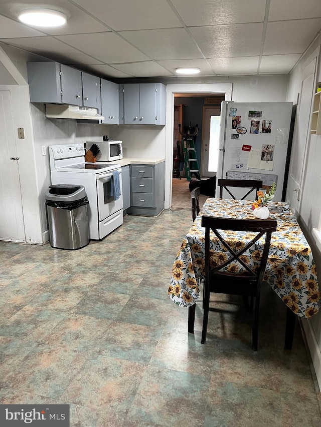 kitchen with gray cabinets, a paneled ceiling, and white appliances