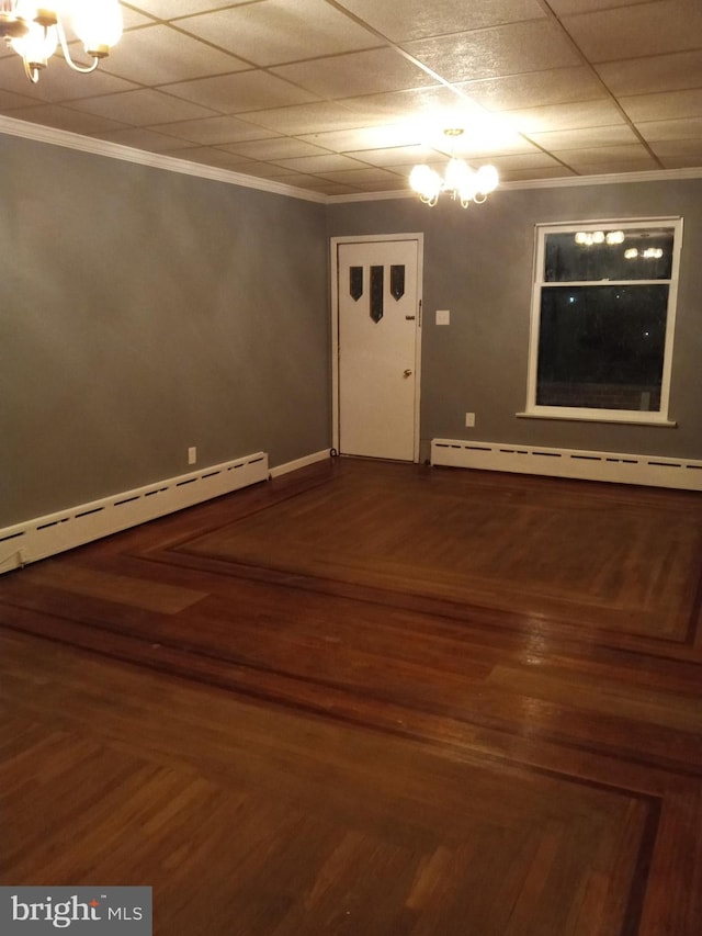 spare room featuring hardwood / wood-style flooring, ornamental molding, a baseboard heating unit, and a chandelier