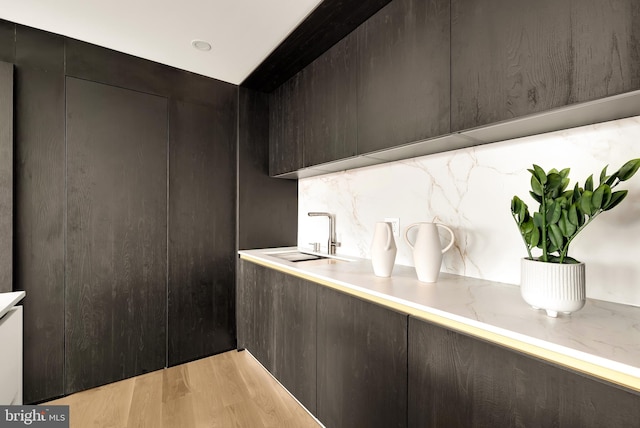 kitchen featuring light stone counters, sink, light hardwood / wood-style floors, and tasteful backsplash